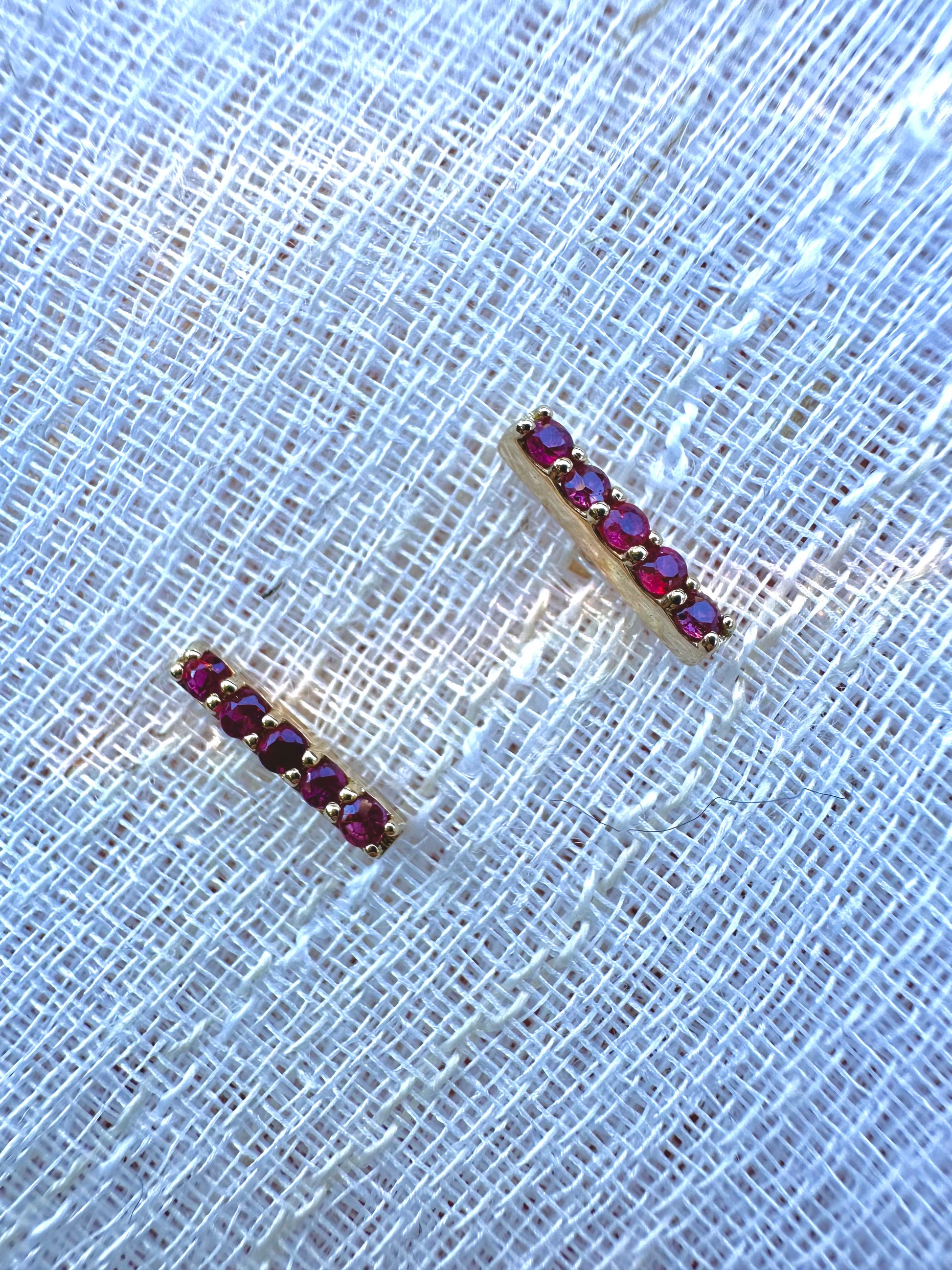 Beautiful and sleek Bar stud earrings adorned with 1.7mm round natural Ruby gemstones. Handcrafted in 18 karat Gold, these Ruby Stud Earrings have a linear design that makes them comfortable for everyday wear. Sold as pair. | Ella Creations Jewelry