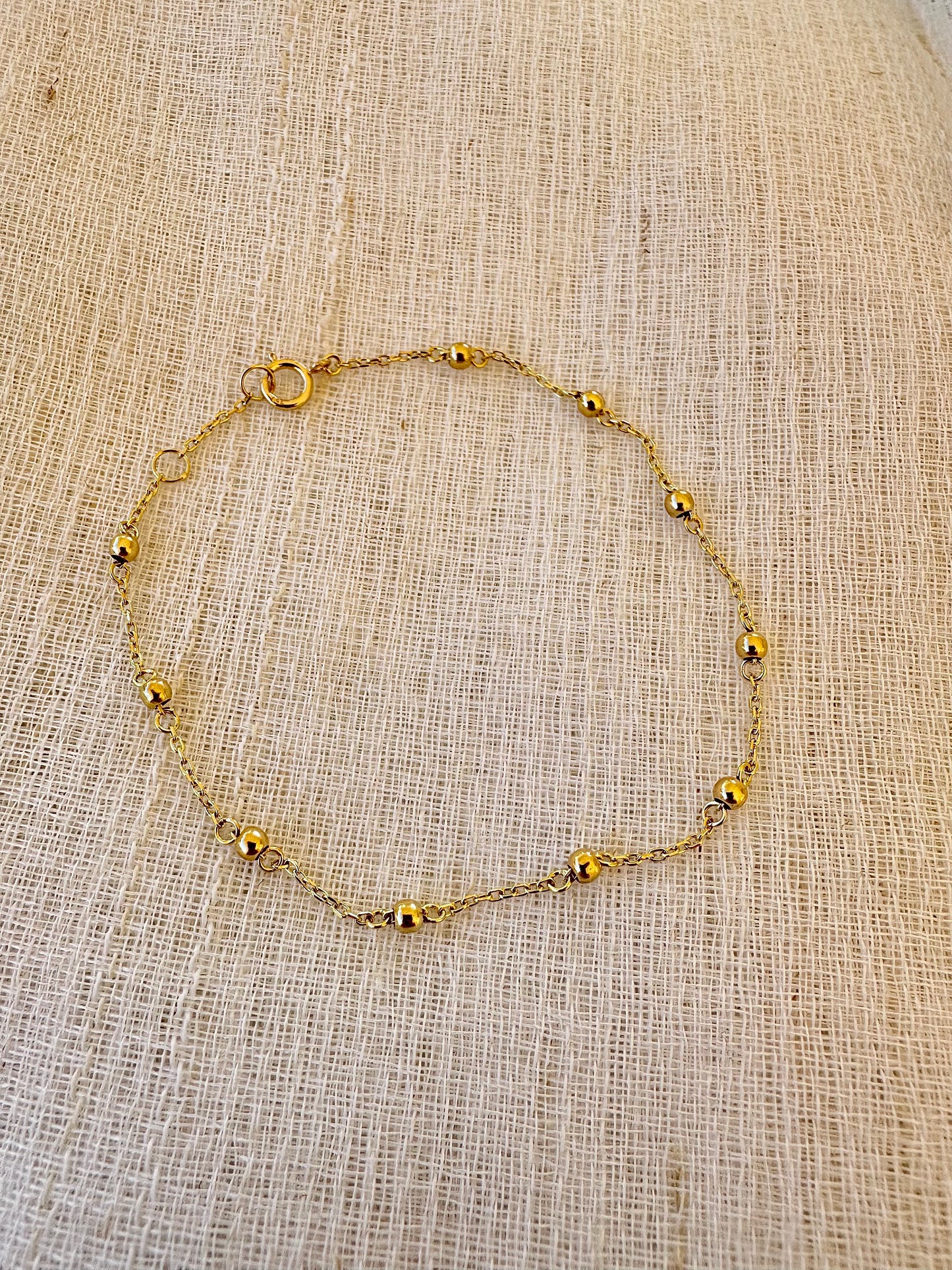 Gold Ball Bracelet featuring gold beads strung seamlessly on a delicate chain.

This Simple Gold bracelet is perfect for a minimalistic stand alone look or for stacking with other bracelets.