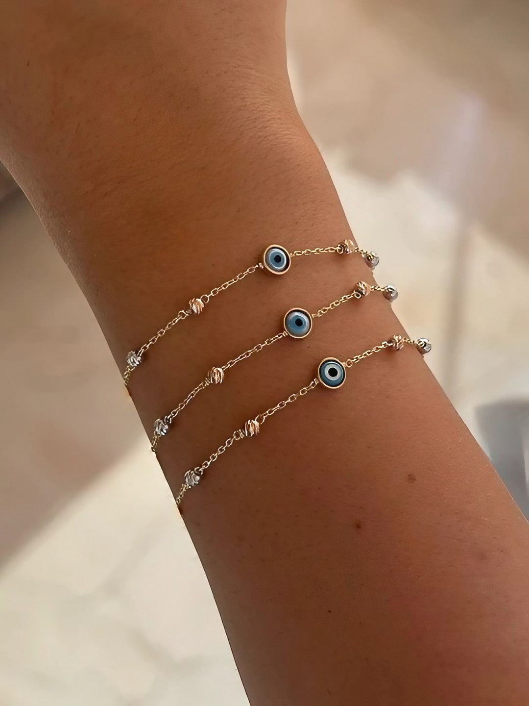 Evil Eye Bracelet featuring an 18 karat chain bracelet with Ojo Turco charm at its center and faceted gold beads adorning the chain.