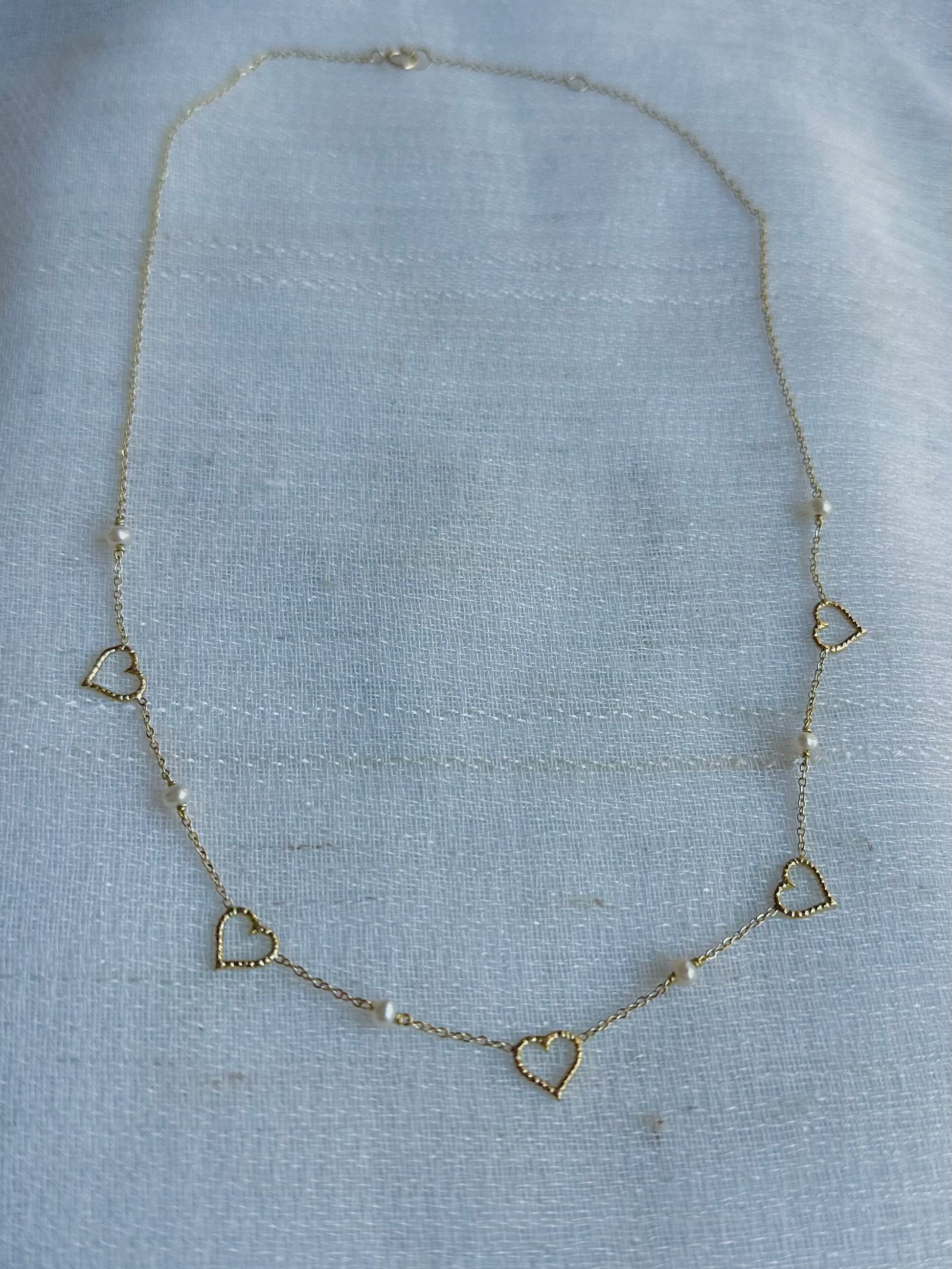 Dainty and light weight solid gold necklace featuring Fresh water Pearls and open-heart charms securely affixed at evenly spaced intervals. This necklace is handcrafted in 18 karat gold ensuring lifetime luster and resistance to tarnishing. | Ella Creations Jewelry