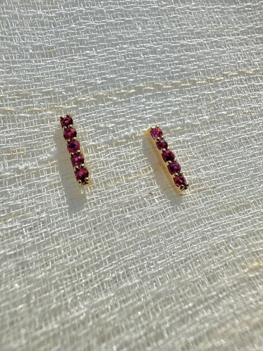 Beautiful and sleek Bar stud earrings adorned with 1.7mm round natural Ruby gemstones. Handcrafted in 18 karat Gold, these Ruby Stud Earrings have a linear design that makes them comfortable for everyday wear. Sold as pair.